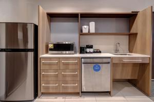 a small kitchen with a refrigerator and a microwave at Home2 Suites By Hilton DeKalb in DeKalb