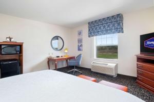 a room with a bed and a desk and a television at Hampton Inn & Suites Rockland in Thomaston