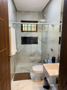 a bathroom with a shower and a toilet and a sink at Chalés Vista da Serra in Piauí