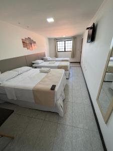 a room with three beds and a window at Pousada La Riviera in Maragogi