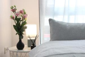 eine Vase mit Blumen auf einem Tisch neben einem Bett in der Unterkunft DREAMSPACE l Kingsize Bett + FREE coffee & cookies in Darmstadt