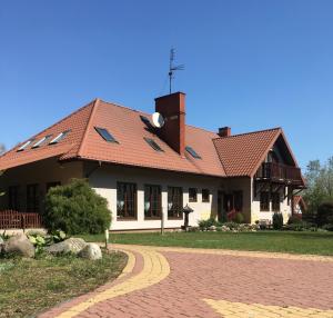 una casa con techo rojo en un camino de ladrillo en Pensjonat u Alexa, en Załuski