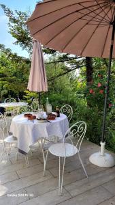 - une table et des chaises avec un parasol sur la terrasse dans l'établissement LA CHEVRIÈRE EN PERIGORD, à Villetoureix