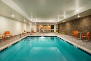 a swimming pool with orange chairs and a brick wall at Home2 Suites by Hilton Roanoke in Roanoke