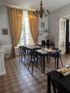 uma sala de jantar com mesas e cadeiras e um lustre em Maison de la Comtesse em Cosne-dʼAllier