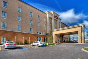 ein Hotel mit zwei Autos auf einem Parkplatz in der Unterkunft Hampton Inn & Suites Rochester/Henrietta in Rochester