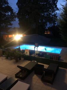 uma piscina à noite com um guarda-sol e mesas em Maison de la Comtesse em Cosne-dʼAllier