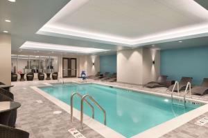 una piscina en una habitación de hotel con sillas y mesas en Hilton Garden Inn Rochester - University & Medical Center en Rochester