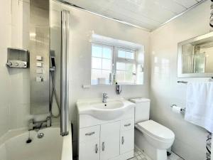ein weißes Bad mit einem Waschbecken und einem WC in der Unterkunft New Luxury Modern House near Airport Free Parking in Luton