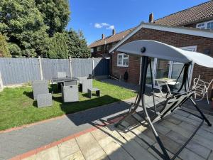 a patio with a table and chairs and an umbrella at New Luxury Modern House near Airport Free Parking in Luton