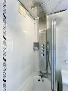 ein weißes Bad mit einer Badewanne und einer Dusche in der Unterkunft New Luxury Modern House near Airport Free Parking in Luton