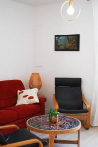 a living room with a red couch and a table at Maison Coté Jardin Amiens - Longueau in Longueau