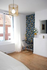 a bedroom with a bed and a chair and a window at Maison Coté Jardin Amiens - Longueau in Longueau