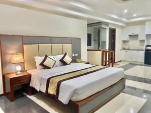 Un dormitorio con una cama grande y una mesa con una lámpara. en In Le Hotel & Apartments, en Hai Phong