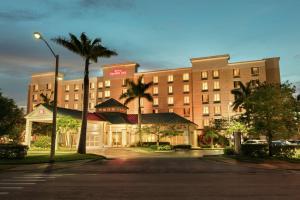 a large hotel with palm trees in front of a street at Hilton Garden Inn Fort Myers Airport/FGCU in Fort Myers