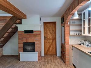a kitchen with a brick fireplace and a wooden door at Dziki brzeg Jezioraka in Plajny