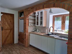 a kitchen with a brick wall and an archway at Dziki brzeg Jezioraka in Plajny
