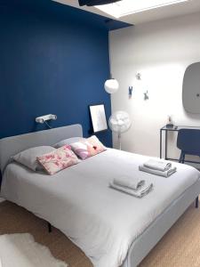 um quarto com uma grande cama branca com paredes azuis em Le loft du chapitre em Saint-Brieuc