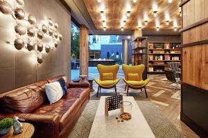 - un salon avec un canapé en cuir et des fauteuils jaunes dans l'établissement Hilton Garden Inn San Diego Downtown/Bayside, CA, à San Diego
