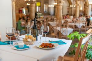 a table with a plate of food and wine glasses at Santuari de Lluc in Lluc