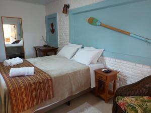 1 dormitorio con cama, mesa y espejo en Pousada Ninhal das Garças, en Ilha Comprida