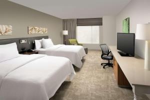 a hotel room with two beds and a flat screen tv at Hilton Garden Inn San Antonio Airport South in San Antonio