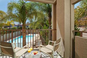 einen Balkon mit Stühlen, einem Tisch und einem Pool in der Unterkunft Hilton Garden Inn San Diego Mission Valley/Stadium in San Diego