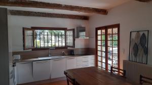 een keuken met witte kasten en een houten tafel bij maison de vacances avec piscine in Berre-des-Alpes