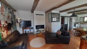 een woonkamer met een zwarte leren bank en een tv bij maison de vacances avec piscine in Berre-des-Alpes
