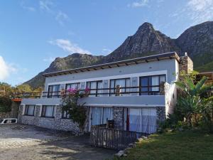 a white house with mountains in the background at Oceanscape in Bettyʼs Bay