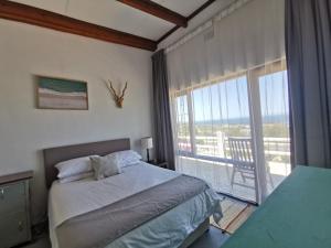a bedroom with a bed and a large window at Oceanscape in Bettyʼs Bay