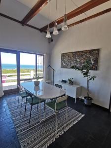 a dining room with a table and chairs and the ocean at Oceanscape in Bettyʼs Bay