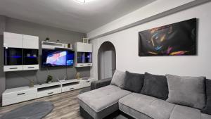 a living room with a gray couch and a tv at MarioApartCentralView in Timişoara