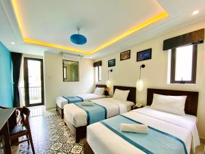 a hotel room with three beds and a table at Grand Holiday Hoian Villa in Hoi An