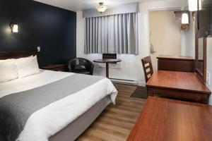 um quarto de hotel com uma cama e uma secretária em Hôtel Marineau Centre em La Tuque