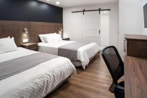 Cette chambre comprend deux lits et un bureau. dans l'établissement Hôtel Marineau Centre, à La Tuque