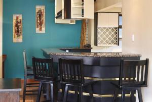 a kitchen with a bar with four chairs around it at Hotel La Amistad in San José