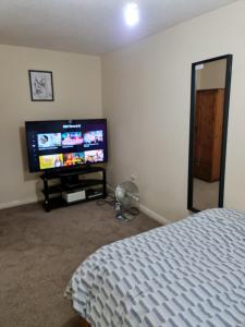 a bedroom with a bed and a flat screen tv at Curly Curves in North Woolwich