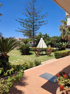 un patio con una mesa y una sombrilla blanca en Green Rooms - Marzamemi, en Pachino