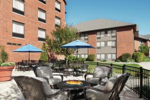 un patio avec des chaises, des tables et des parasols dans l'établissement Hilton Garden Inn South Bend, à South Bend