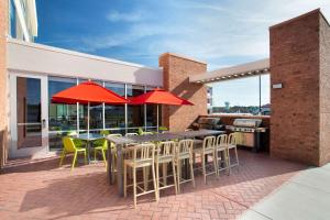 a patio with tables and chairs and red umbrellas at Home2 Suites By Hilton Lewes Rehoboth Beach in Lewes