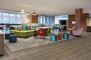 - un hall avec un canapé vert, des tables et des chaises dans l'établissement Home2 Suites By Hilton Lewes Rehoboth Beach, à Lewes