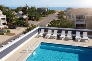 a swimming pool with chairs and the ocean in the background at Fenwick Shores, Tapestry Collection by Hilton in Fenwick Island