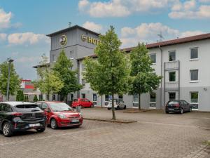 eine Gruppe von Autos, die auf einem Parkplatz vor einem Gebäude geparkt sind in der Unterkunft B&B Hotel Hannover-Lahe in Hannover