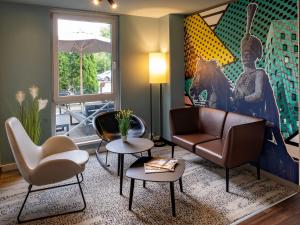 sala de estar con sofá, sillas y una pintura en B&B Hotel Hannover-Lahe, en Hannover