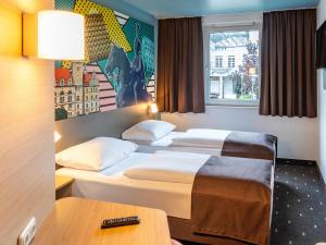 a hotel room with two beds and a table at B&B Hotel Hannover-Lahe in Hannover