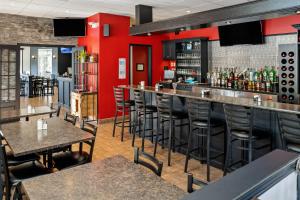 - un bar dans un restaurant avec des murs rouges et des tabourets dans l'établissement Hôtel Marineau La Tuque, à La Tuque