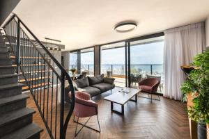 a living room with a couch and chairs and a staircase at Stunning 2BR Apartment with Balcony and Ocean View in the Heart of Haifa by Sea N' Rent in Haifa