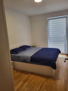 een slaapkamer met een bed met blauwe lakens en een raam bij Luxurios Apartment Sarajevo in Sarajevo