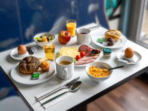 bandeja de desayuno con alimentos para el desayuno y bebidas en una mesa en B&B Hotel Hannover-Lahe, en Hannover